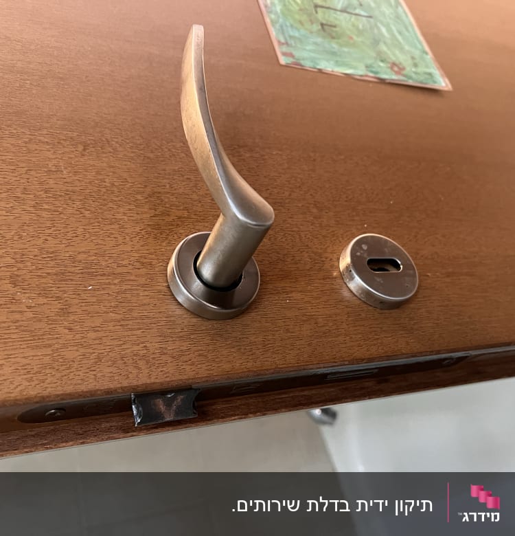 ידית דלת מתכתית על דלת עץ